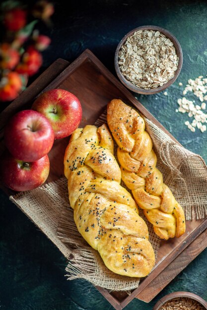 Top view cable-knit breadsticks apples on rectangle wood board oats bowl on table