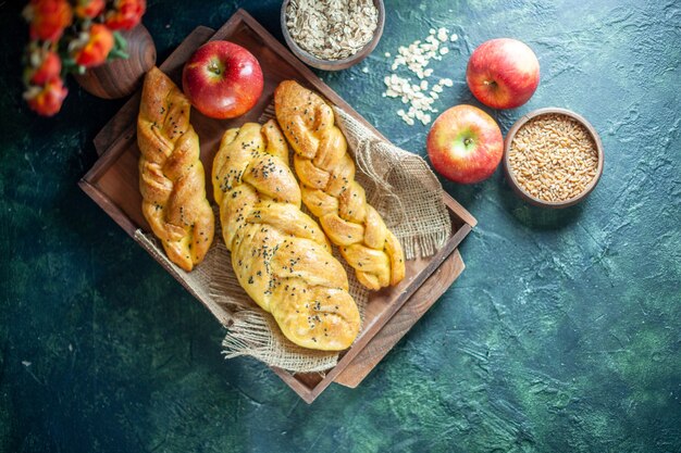 Top view cable-knit breadsticks on rectangle wood board apples on table free space