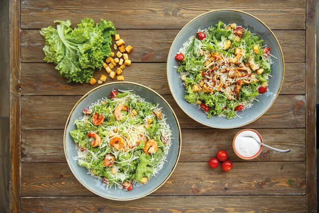 Top view of caesar salad plates with shrimps and chicken slices