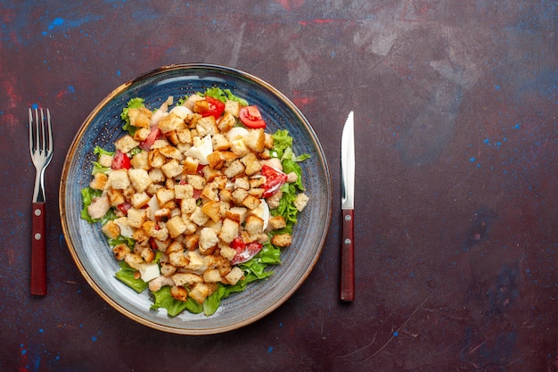 Top view caesar salad with sliced vegetables and rusks on dark floor vegetable salad food lunch meal rusk taste