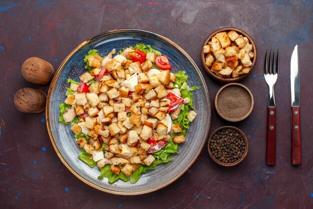 Вид сверху салат цезарь с нарезанными овощами и сухариками внутри тарелки на темном столе овощной салат еда обед еда сухарик