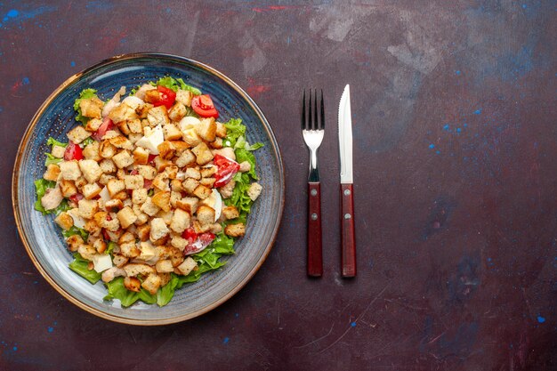 暗い壁のプレートの内側にスライスした野菜とラスクを添えた上面シーザーサラダ野菜サラダ食品ランチ食事ラスク味