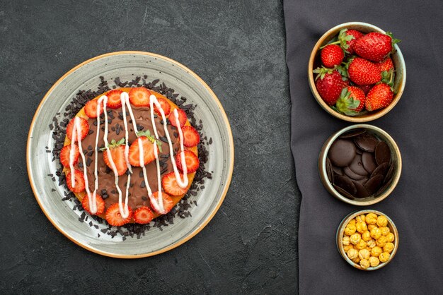 테이블보에 헤이즐넛 딸기와 초콜릿을 넣은 탑 뷰 케이크 그릇, 블랙 테이블에 초콜릿과 딸기를 넣은 케이크