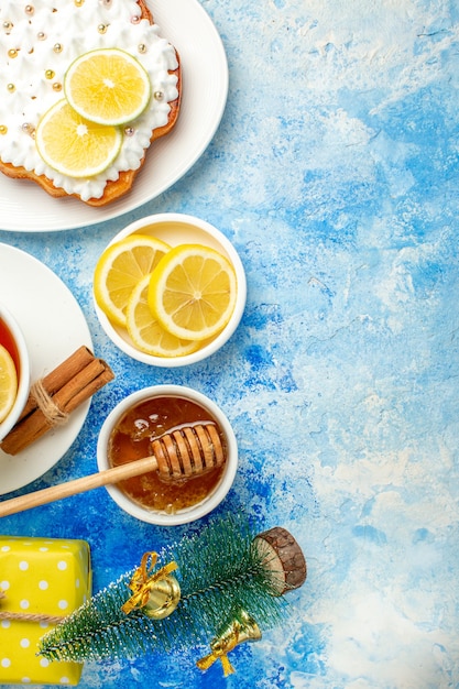 Top view cake on plate lemon slices honey in bowl small xmas tree on blue table free space