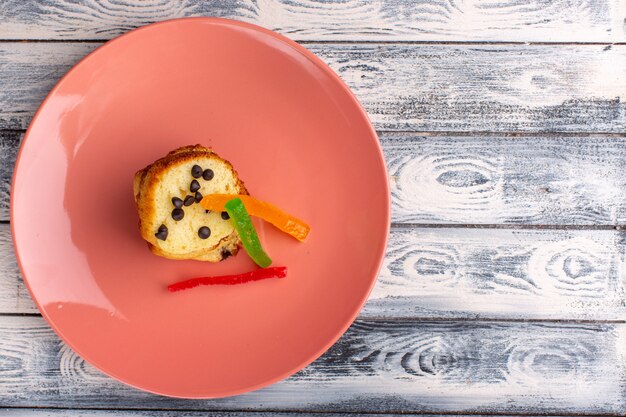 Foto gratuita vista dall'alto della fetta di torta all'interno del piatto marrone con choco chips e marmellata sulla superficie chiara