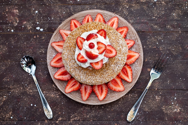 A top view cake slice with cream and fresh red strawberries inside plate on the dark background