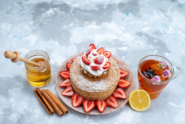青灰色の背景にお茶とプレートの内側のクリームの新鮮な赤いイチゴの平面図ケーキスライス
