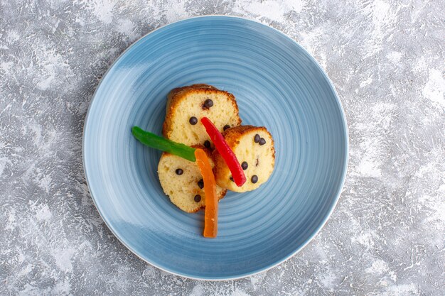 Top view of cake slices inside blue plate with choco chips and marmalade on rustic grey surface