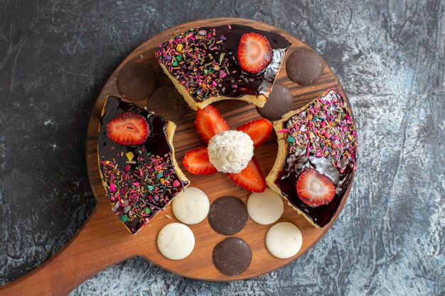 Top view cake slices with cookies on a dark-light surface