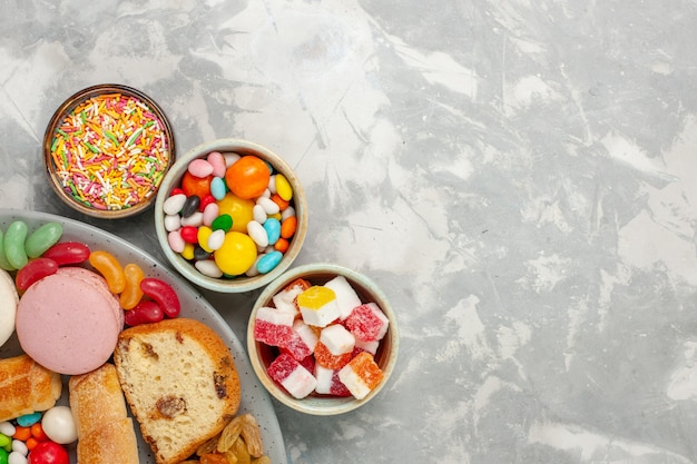 Vista dall'alto di fette di torta con macarons e caramelle