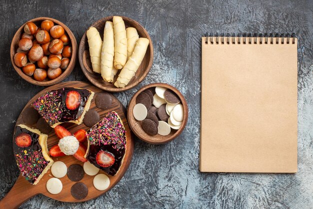 Top view cake slices with nuts and cookies on a dark surface