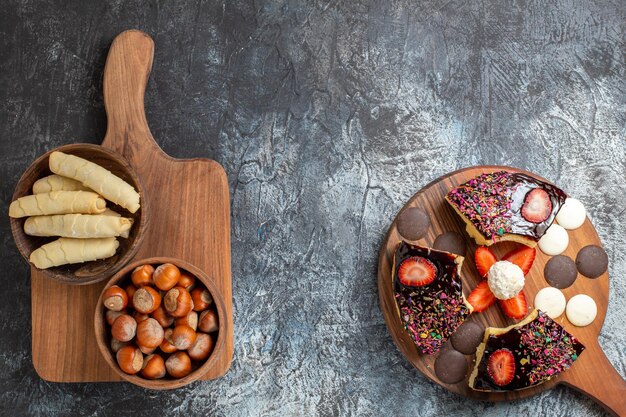 Top view cake slices with nuts and sweets on dark surface