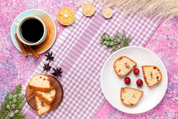 ピンクの机の上のコーヒーとプレートの内側にイチゴが入った上面図のケーキスライスケーキは甘いビスケットシュガーを焼くカラー写真