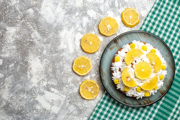 Бесплатное фото Вид сверху торт с кондитерским кремом и лимоном на круглом блюде на зеленой белой клетчатой скатерти
