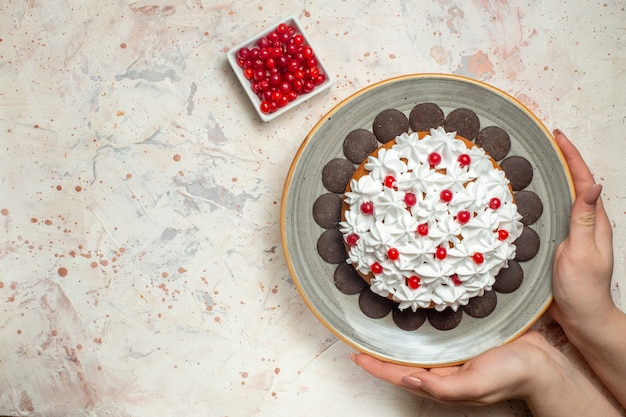 Top view cake with pastry cream and chocolate in female hand berry in bowl