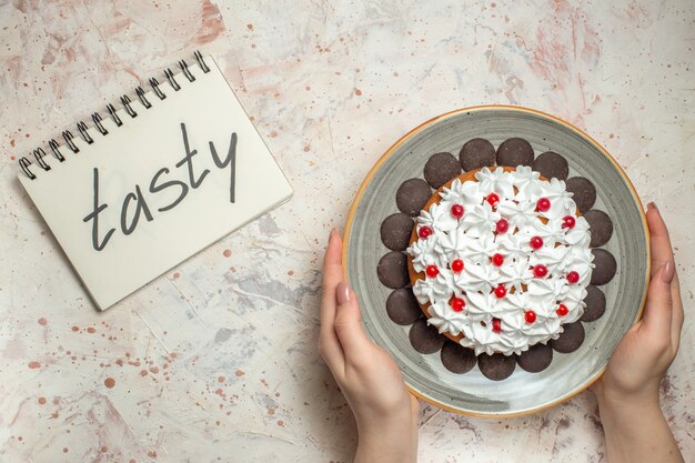 노트북에 쓰여진 맛있는 여성 손에 과자 크림과 초콜릿 상위 뷰 케이크