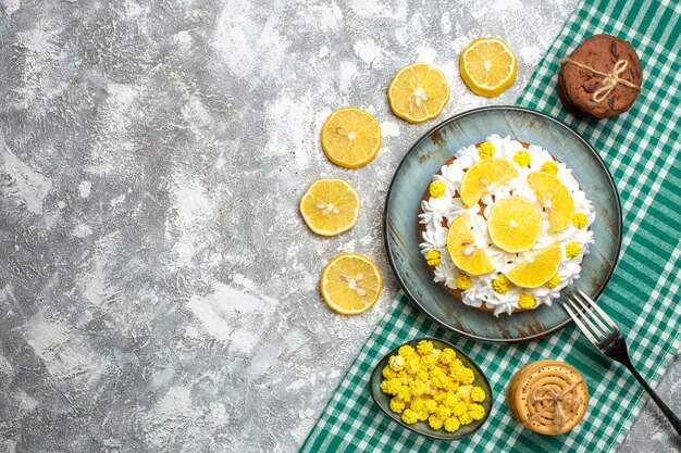 Foto gratuita torta vista dall'alto con crema pasticcera e forchetta al limone su piatto di biscotti caramelle in ciotola su tovaglia a scacchi bianca verde