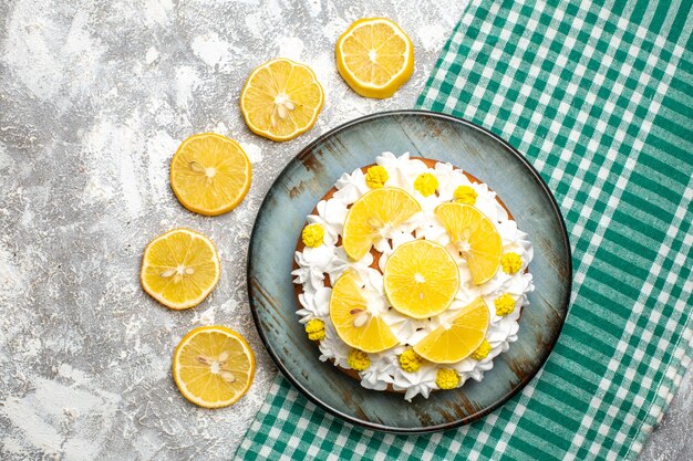 Top view cake with pastry cream and lemon on platter on green white checkered tablecloth