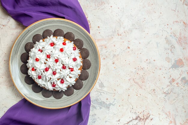 Top view cake with pastry cream on plate purple shawl