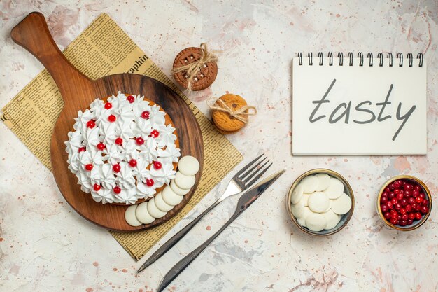 Top view cake with pastry cream on wood board. tasty written on notebook