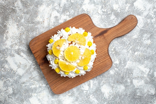 Top view cake with white cream and lemon slices on cutting board