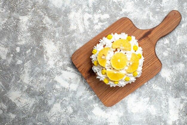 Top view cake with white cream and lemon slices on cutting board