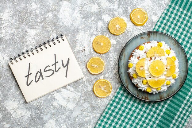 Free photo top view cake with white cream and lemon slices on platter on green white checkered tablecloth