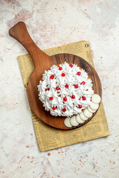 Top view cake with white pastry cream on cutting board on newspaper