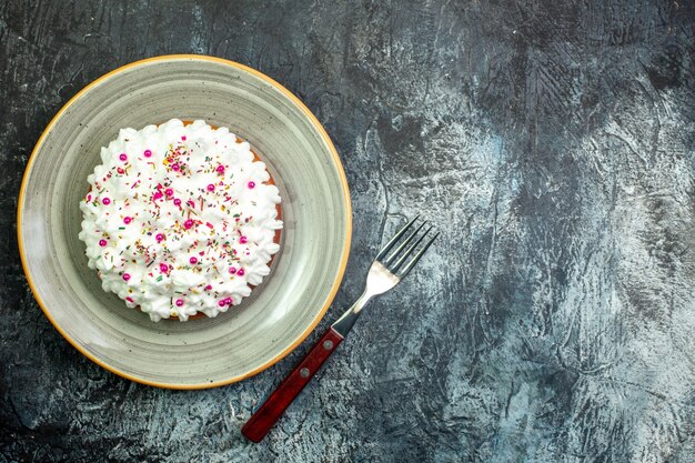 Top view cake with white pastry cream on grey round platter fork on grey table with copy place