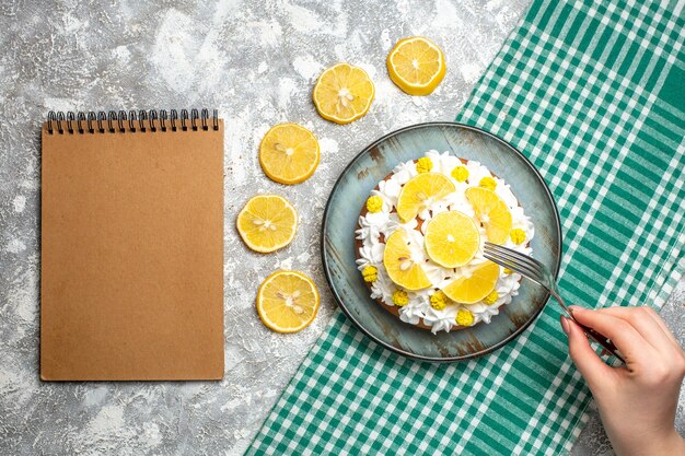 Top view cake with white pastry cream and lemon fork in female hand