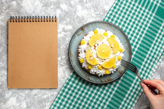 둥근 접시에 흰 생 과자 크림과 레몬 조각이있는 상위 뷰 케이크