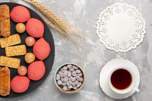 Top view cakes and bagels with candies and crackers inside plate on light-white background cake biscuit cookie sugar sweet pie