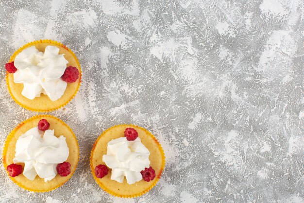 Top view cakes with cream yummy baked designed with raspberry on the grey background sweet bake biscuit cream