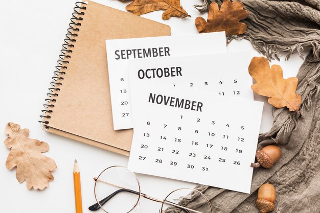 Top view of calendar with glasses and autumn leaves