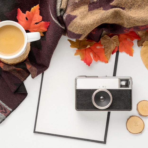 Top view of camera with autumn leaves and coffee