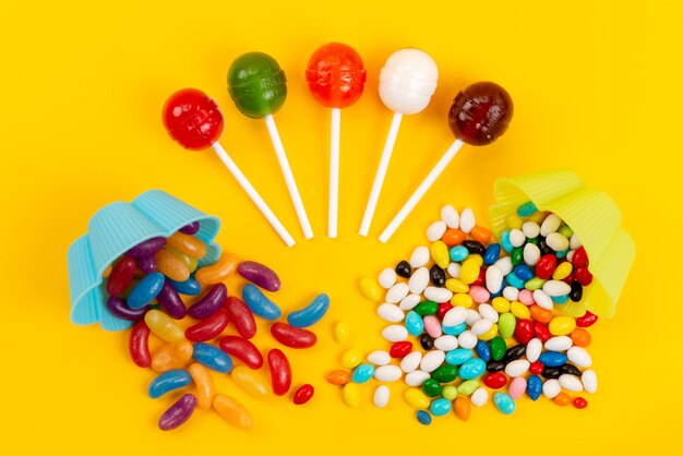 Вид сверху сладкие вкусные конфеты и леденцы, изолированные на желтом