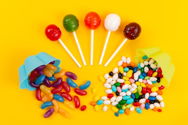 A top view candies and lollipops sweet tasty isolated on yellow