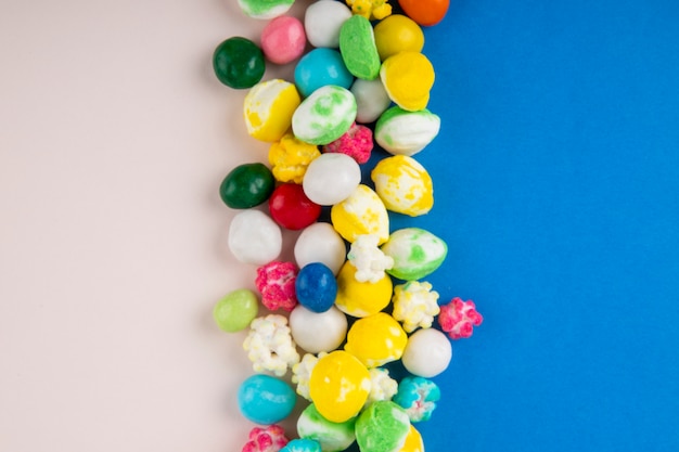 Free photo top view of candies in multi-colored glaze on blue and white background with copy space