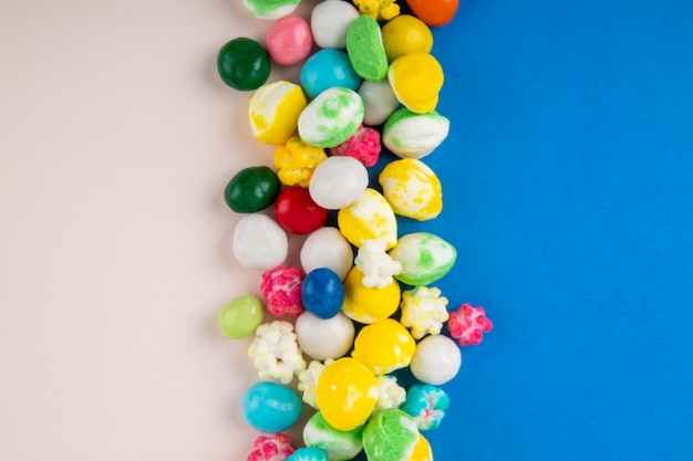 Top view of candies in multi-colored glaze on blue and white background with copy space
