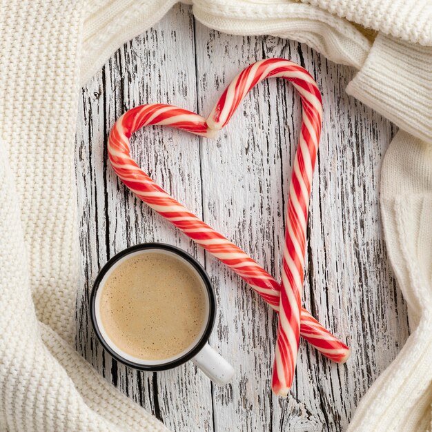 Top view of candy canes in heart shape with cup of hot cocoa