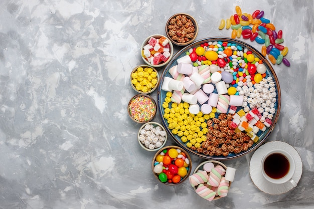 Бесплатное фото Вид сверху конфетной композиции разноцветные конфеты с зефиром и чаем на белом столе сахарные конфеты конфеты сладкие конфитюры