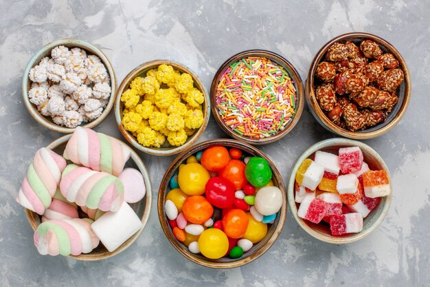 Top view candy composition different colored candies with marshmallow inside pots on the white desk sugar candy bonbon sweet confiture