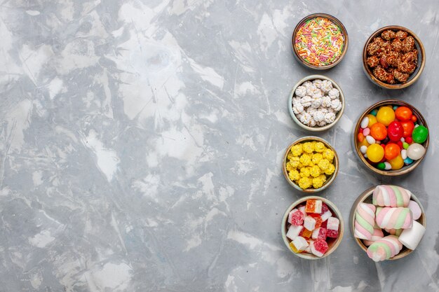 Top view candy composition different colored candies with marshmallow inside pots on white wall sugar candy bonbon sweet confiture