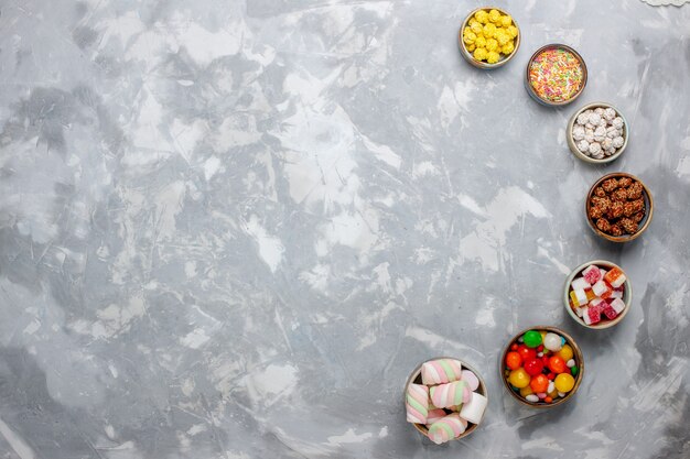 Top view candy composition different colored candies with marshmallow on the white desk sugar candy bonbon sweet confitures tea