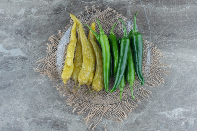 Top view of canned and fresh green peppers . 