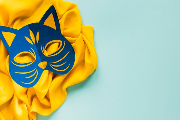 Top view of carnival feline mask on textile with copy space