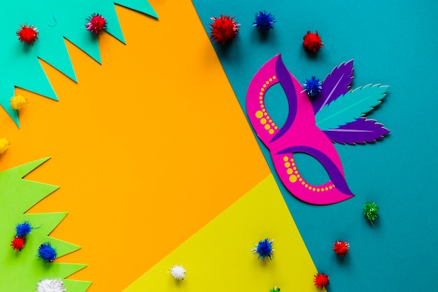 Top view of carnival mask and colorful pom-poms