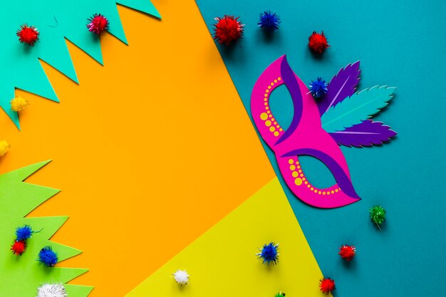 Top view of carnival mask and colorful pom-poms