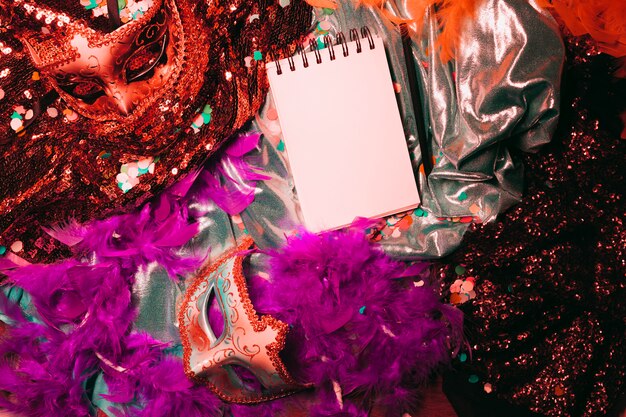 Top view of carnival mask; soft feather boa and blank spiral notepad
