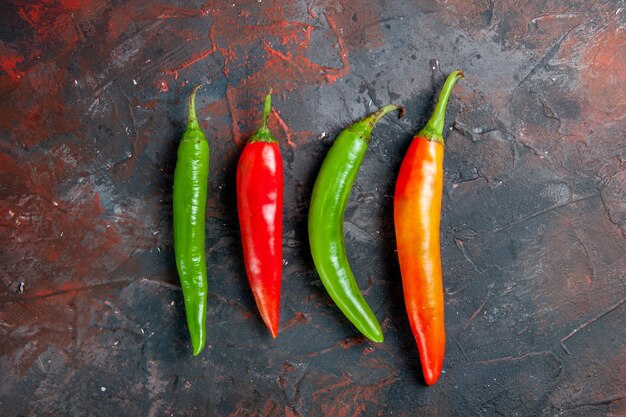 Top view of cayenne peppers in different colors and sizes on mixed color background